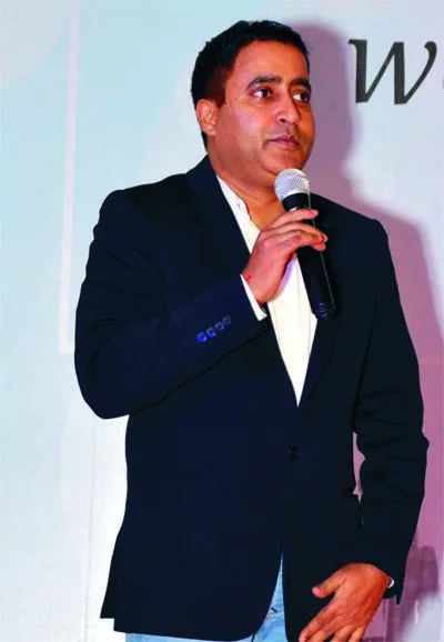 Man in a suit speaking into a microphone at an event